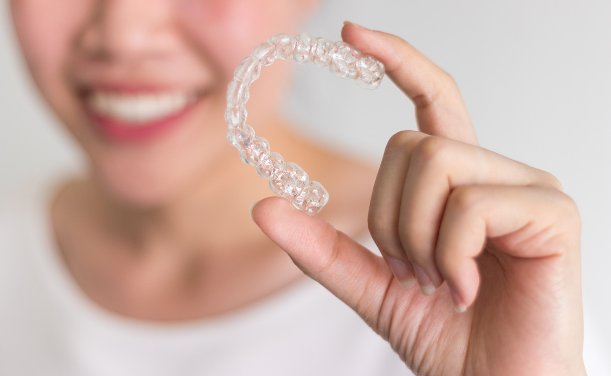 smiling woman holding invisalign-invisible braces