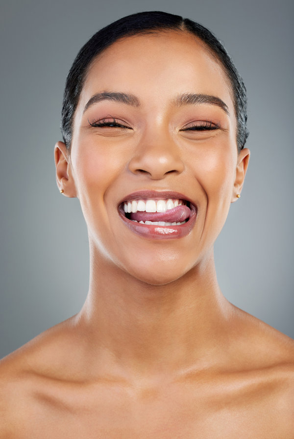 Woman, tongue out and studio for oral health, smile and teeth whitening results on gray background. Female person, cosmetics and braces or veneers transformation, treatment and dental confidence.