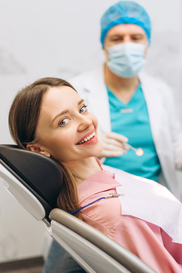 Portrait of happy female patient satisfied after dental treatment in a dentist office, looking at camera. Healthcare dental treatment
