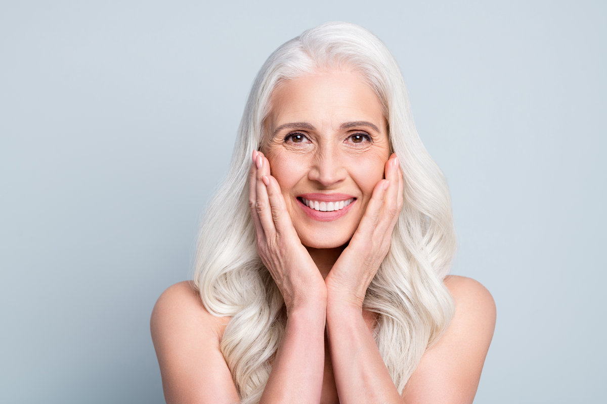 Close-up portrait of her she nice attractive cheerful grey-haired elderly lady touching silky skin cleansing isolated on gray pastel color background.