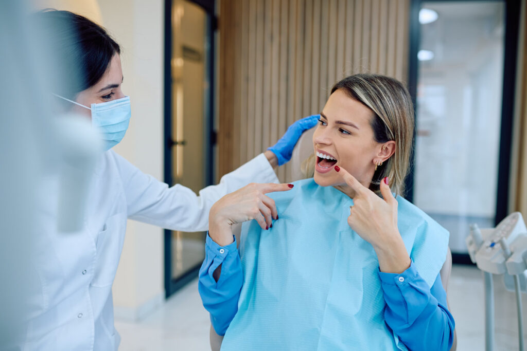 Woman patient showing healthy tooth to dentist