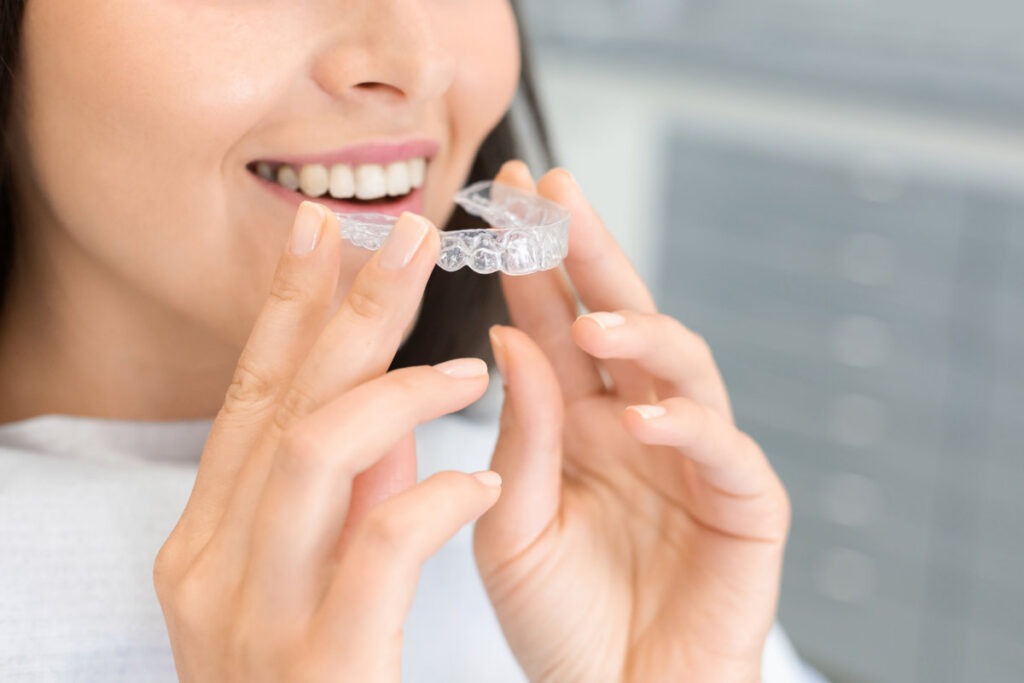Dental Treatment Concept. Cropped image of young woman holding invisible braces, whitening tray, free space