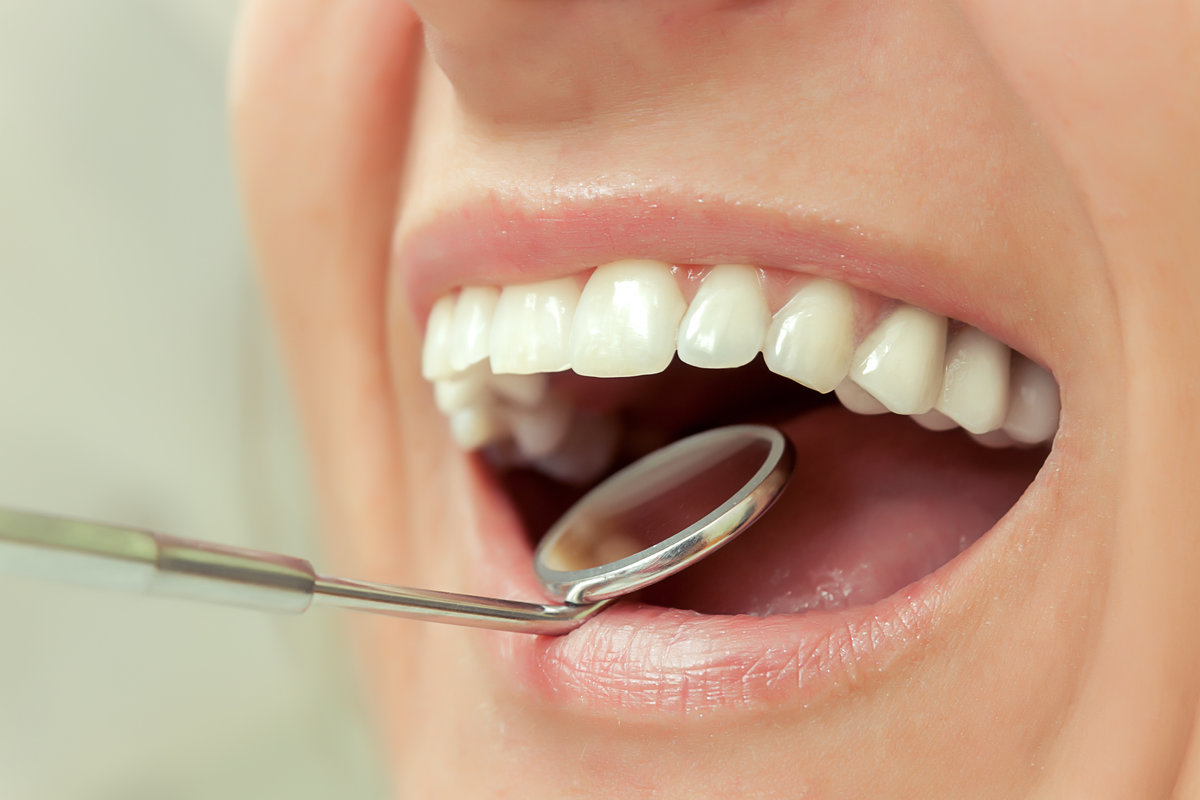 Close-up of patients open mouth during oral checkup with mirror near by