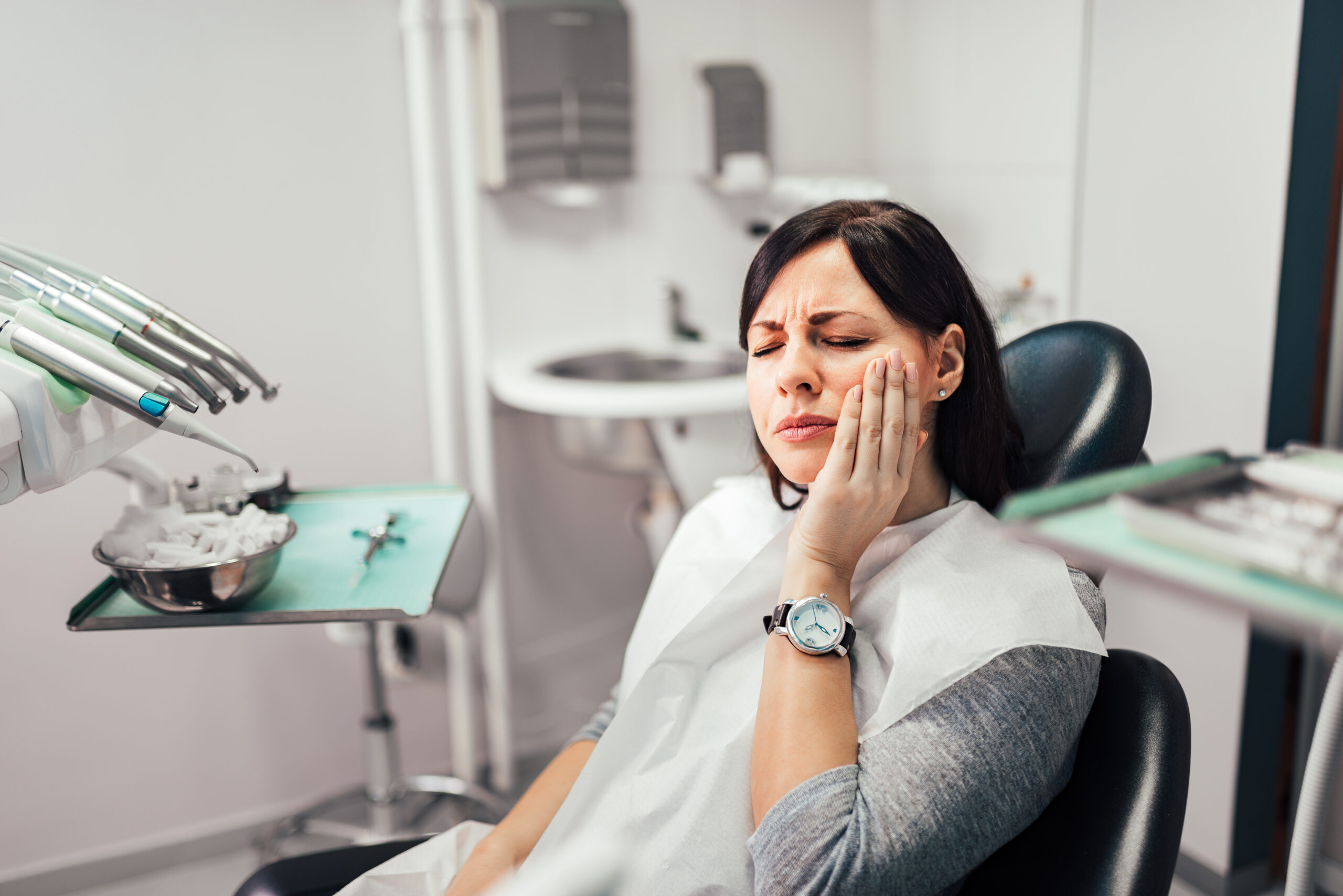 Woman experiencing tooth pain at the dentist office