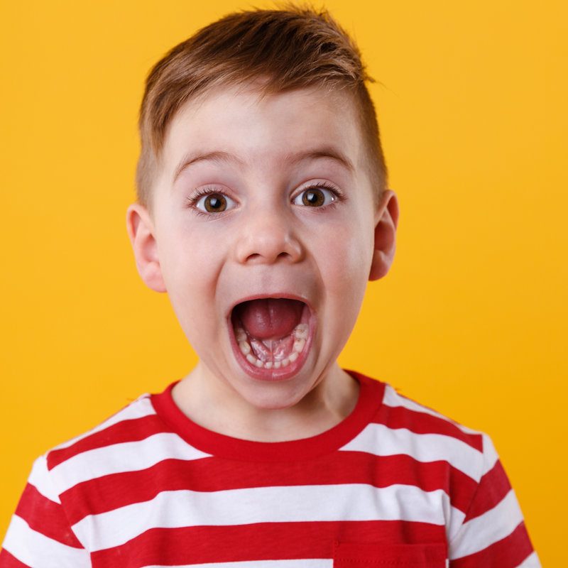 Close up portrait of a little boy screaming out loud isolated over orange background