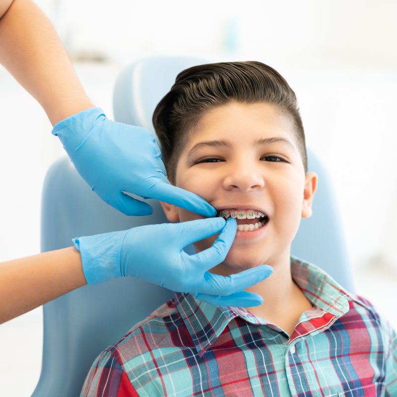 Female orthodontist examining cute boy wearing braces