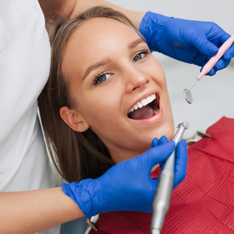 Close-up of female patient having her teeth examined by specialist in dental clinic.